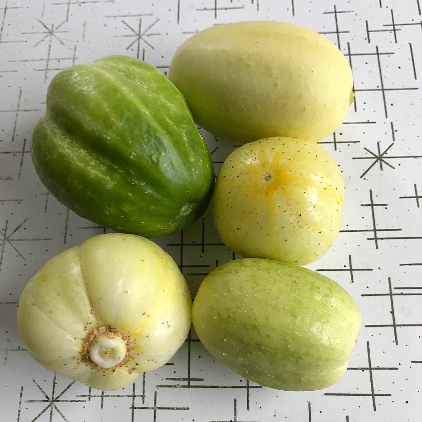 Five different apple cucumbers on a table.