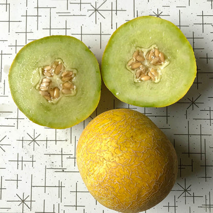 Netted galia melon cut in half, next to a whole melon.