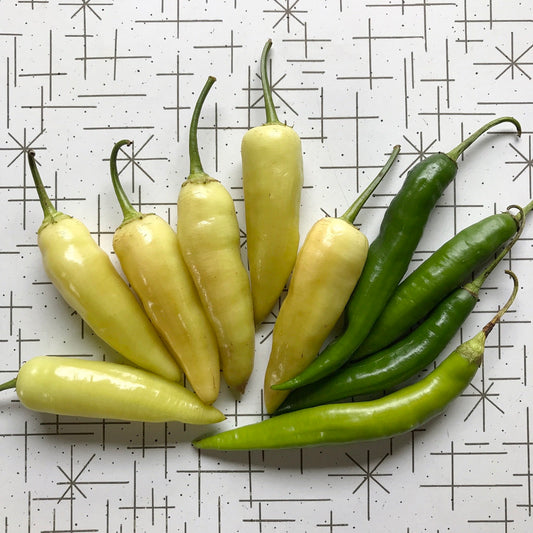 Green and yellow aji peppers on a table.