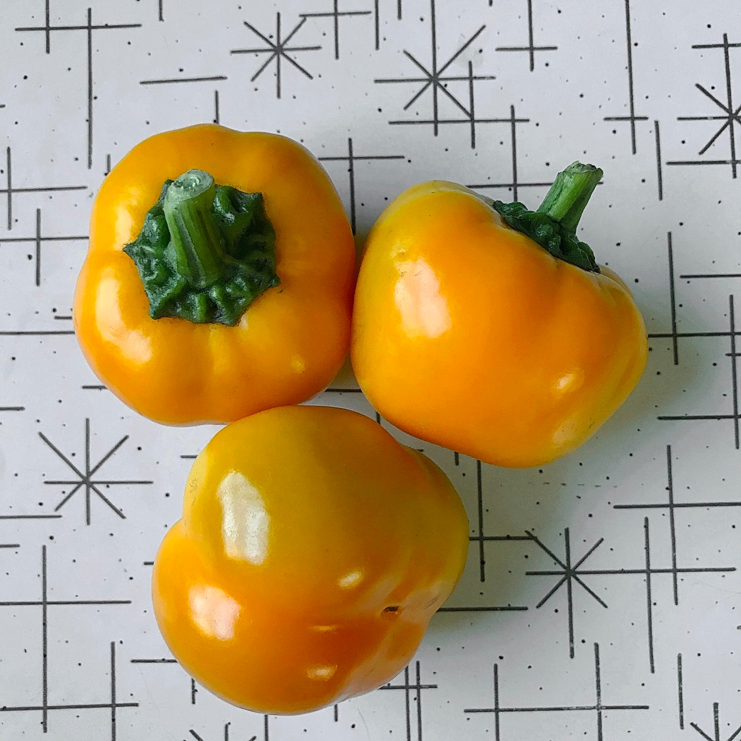 Three orange peppers on a table.