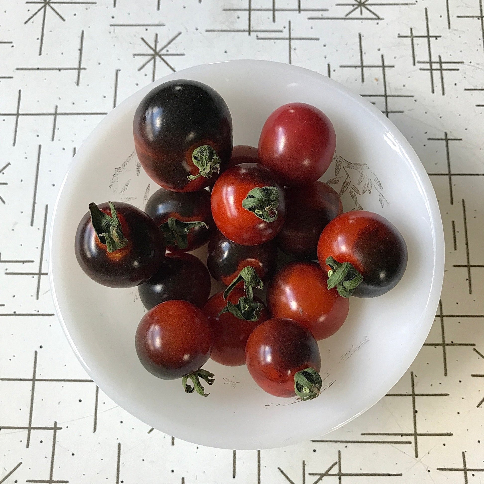 Red cherry tomatoes with antho shoulders in a small bowl.